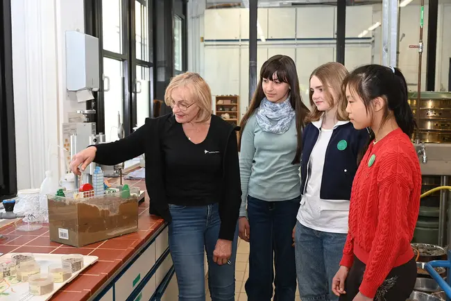 Eine Mitarbeiterin der Hochschule RheinMain zeigt Teilnehmerinnen am Girls’Day 2026 in einem Labor eine Experimentieranordnung.