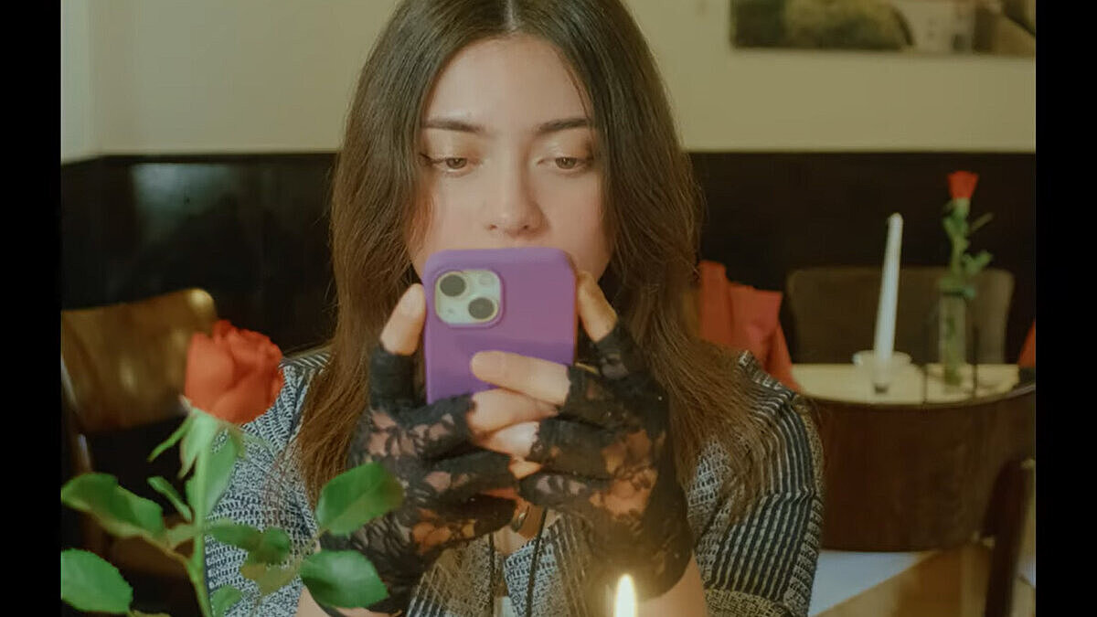 Filmstill aus dem prämierten Kurzfilm „Gesendet“ von Moritz Pähler. Die Szene zeigt eine junge Frau, die auf ihr Smartphone starrt.