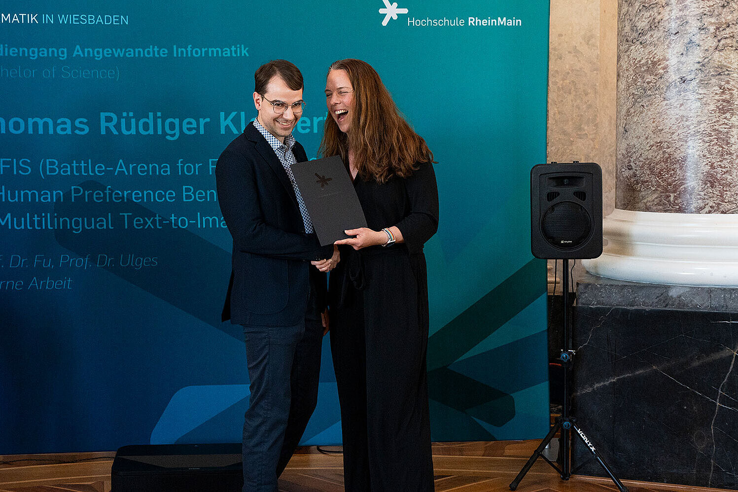 Prof. Dr. Eva-Maria Iwer überreicht einem Absolventen seine Abschlussurkunde.