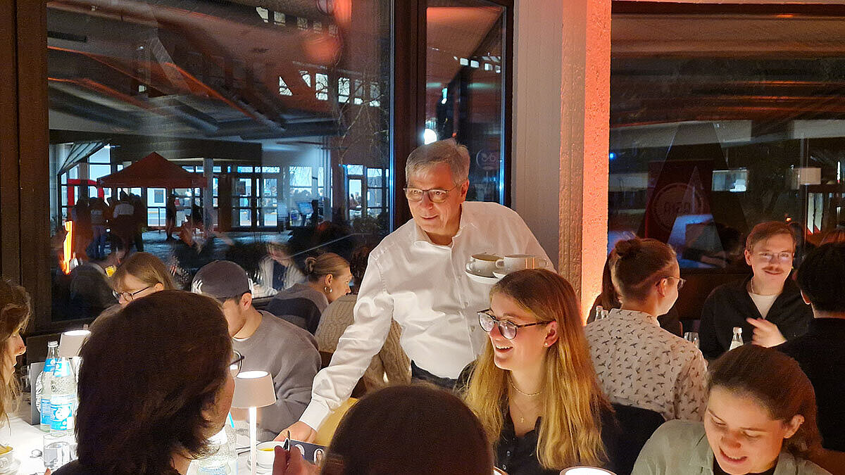 Gert-Uwe Mende bringt den Studierenden Suppe als Vorspeise an den Tisch