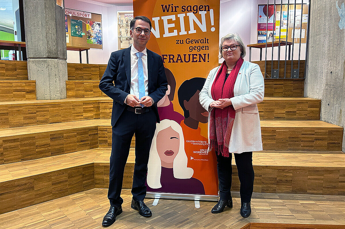 Der hessische Justizminister Christian Heinz steht gemeinsam mit Hochschulpräsidentin Prof. Dr. Eva Waller vor einem Roll-up des Frauen- und Gleichstellungsbüros der Hochschule RheinMain.