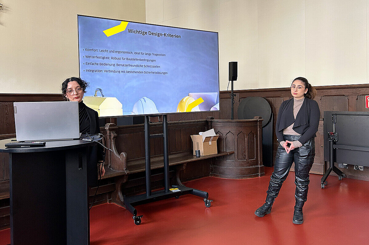 Zwei Studentinnen der Hochschule RheinMain präsentieren an einem großen Bildschirm ihre Geschäftsidee im Rahmen des Green Innovation Camps.
