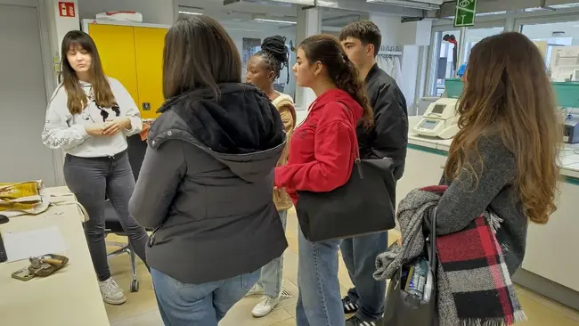 A group of five students in a lab with academic staff member