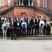 Die Absolvent:innen der Informatik an der HSRM stehen für ein Gruppenfoto mit ihren Urkunden vor dem Schloss Biebrich.