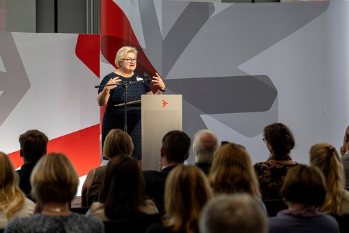 Hochschulpräsidentin Prof. Dr. Eva Waller steht während ihrer Begrüßung auf der Bühne und spricht zum Publikum