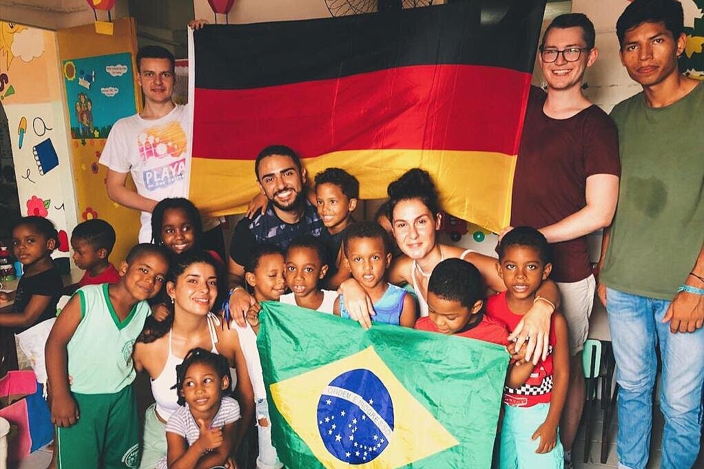 Jeremias Herner Eine Gruppe von Kindern und jungen Erwachsenen posiert für die Kamera, sie halten eine Deutschland- und eine Brasilienflagge in Richtung der Kamera