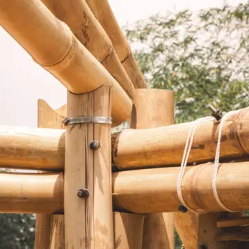 The image shows a close-up of bamboo canes that are artfully connected. The structures appear to be part of an architectural design, showcasing the natural texture of the bamboo.