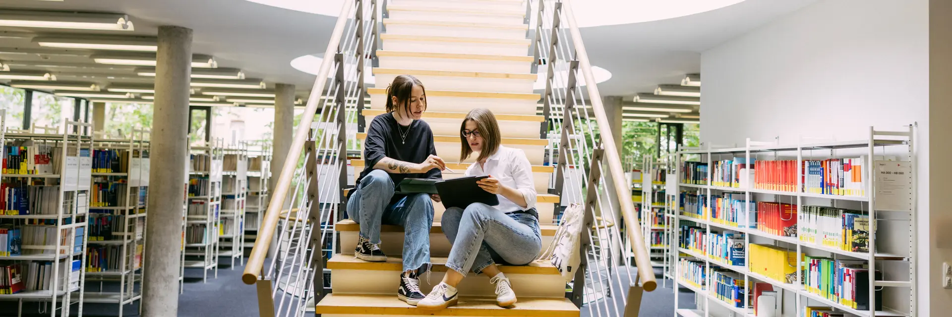 Studierende sitzen auf einer Treppe in der Bibliothek der Wiesbaden Business School