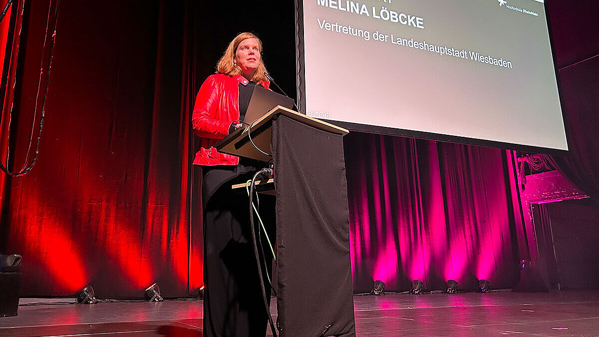 Milena Löbcke, Dezernentin für Gesundheit, Integration und Verbraucherschutz der Landeshauptstadt Wiesbaden, steht auf der Bühne des Schlachthofs und begrüßt die Studierenden.