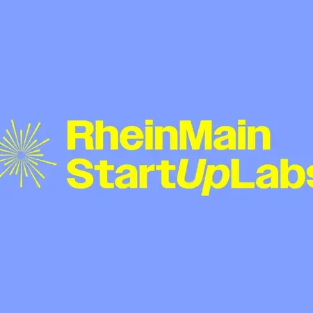 Das Bild zeigt den Schriftzug "RheinMain StartUpLabs" in gelber Schrift auf einem blauen Hintergrund. Neben dem Text befinden sich grafische Elemente, die an eine Sonne oder einen Stern erinnern.