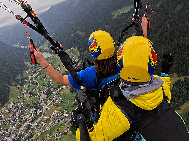 Zwei Paraglider fliegen über eine Landschaft