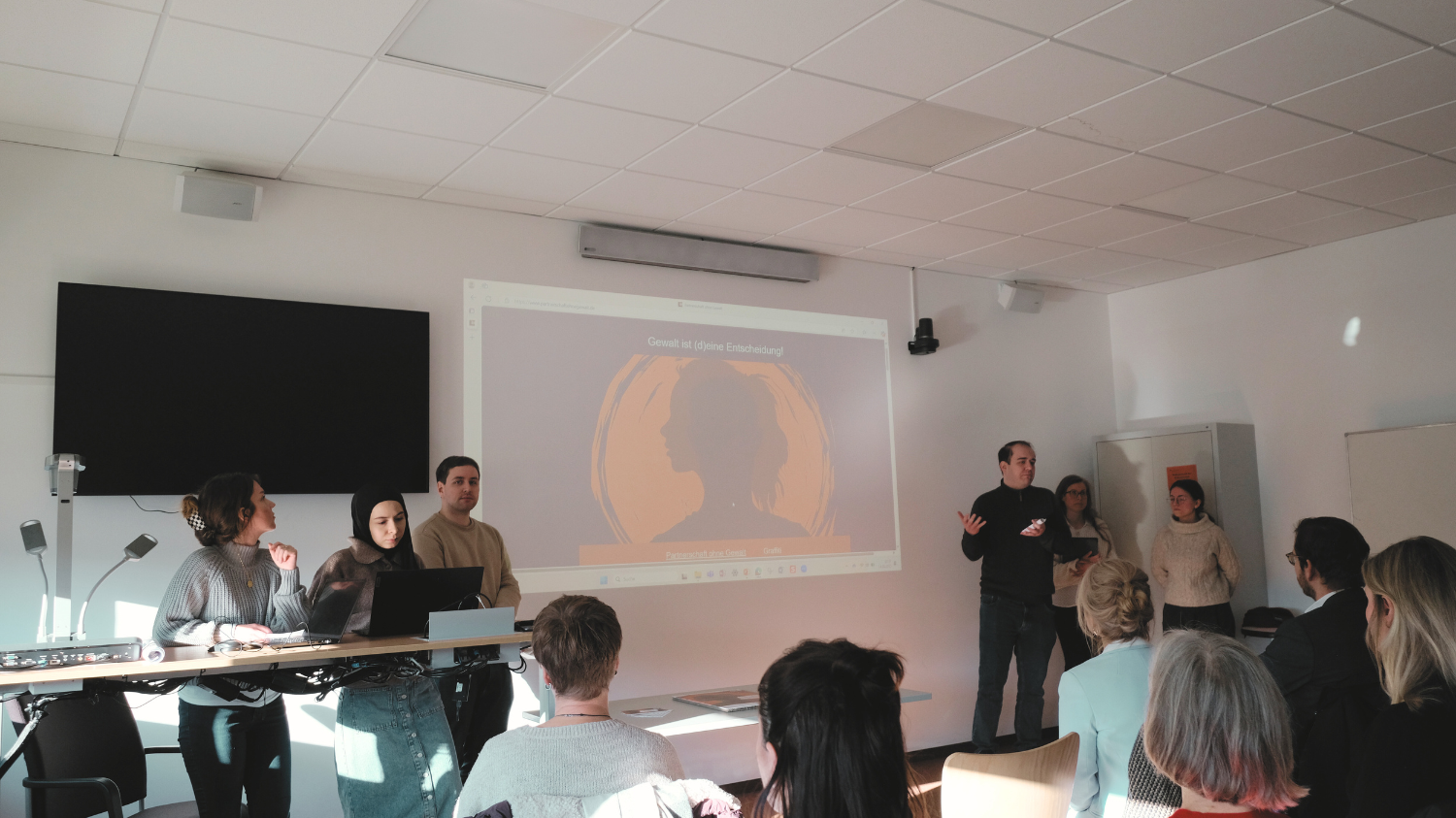 mehrere Menschen halten eine Präsentation/ Vortrag vor einer Gruppe 
