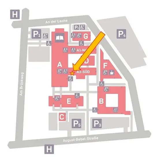 Eine Übersichtskarte eines Geländes zeigt die verschiedenen Gebäude und Parkplätze. Der Standort "A2-SÜD" ist orange eingezeichnet und durch einen Pfeil hervorgehoben. Die angrenzenden Bereiche sind mit Buchstaben und Farben gekennzeichnet.