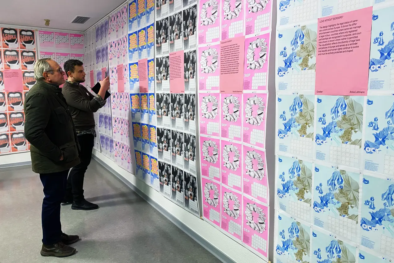 Zwei Personen sehen sich die Motive des Hochschulkalenders 2026 an.