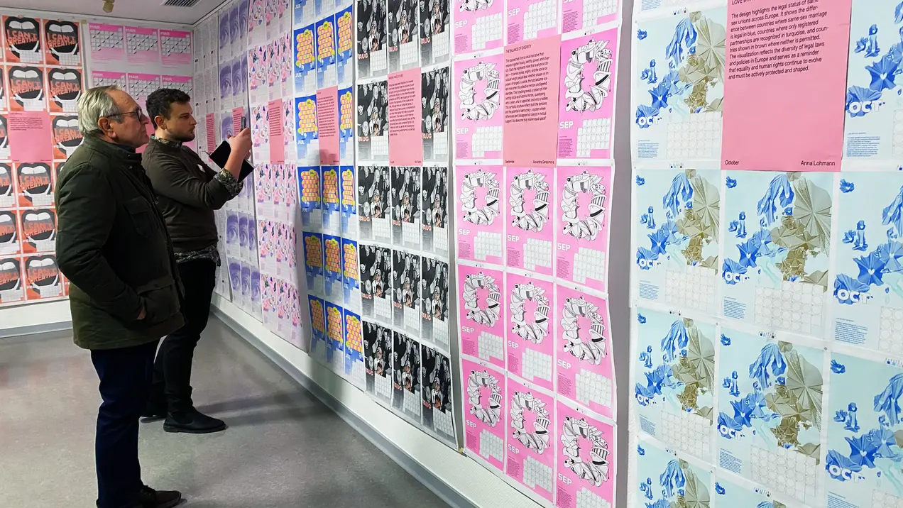 Zwei Personen sehen sich die Motive des Hochschulkalenders 2026 an.