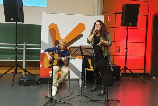 Benedikt Herrmann (Gitarre) und Anastasia Kruse (Gesang) während ihres Auftritts auf der Abschlussfeier des Studienbereichs Angewandte Physik und Medizintechnik