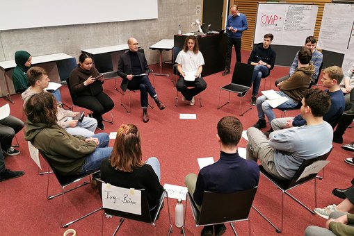 Studierende des Studiengangs Mobilitätsmanagement während des Planspiels in einem Stuhlkreis, Prof. Dr. André Bruns moderiert