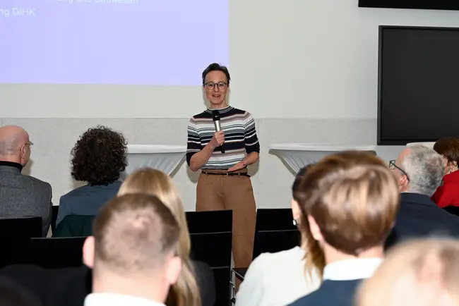 Sofie Geisel, Hauptgeschäftsführung DIHK, steht auf einer Bühne und spricht mit einem Mikrofon zum Publikum des 2. Wiesbadener Tag für sozial nachhaltiges Investieren an der Hochschule RheinMain.