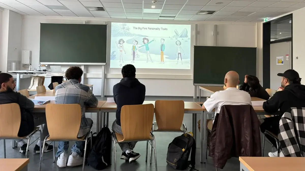 Ein Lehrsaal mit mehreren Personen, die einem Vortrag im Rahmen der Winterschool 2026 zuhören. An der Wand ist eine Präsentation zu sehen, die die fünf großen Persönlichkeitseigenschaften zeigt. Die Zuhörer sind aufrecht in ihren Stühlen und blicken auf die Folie.