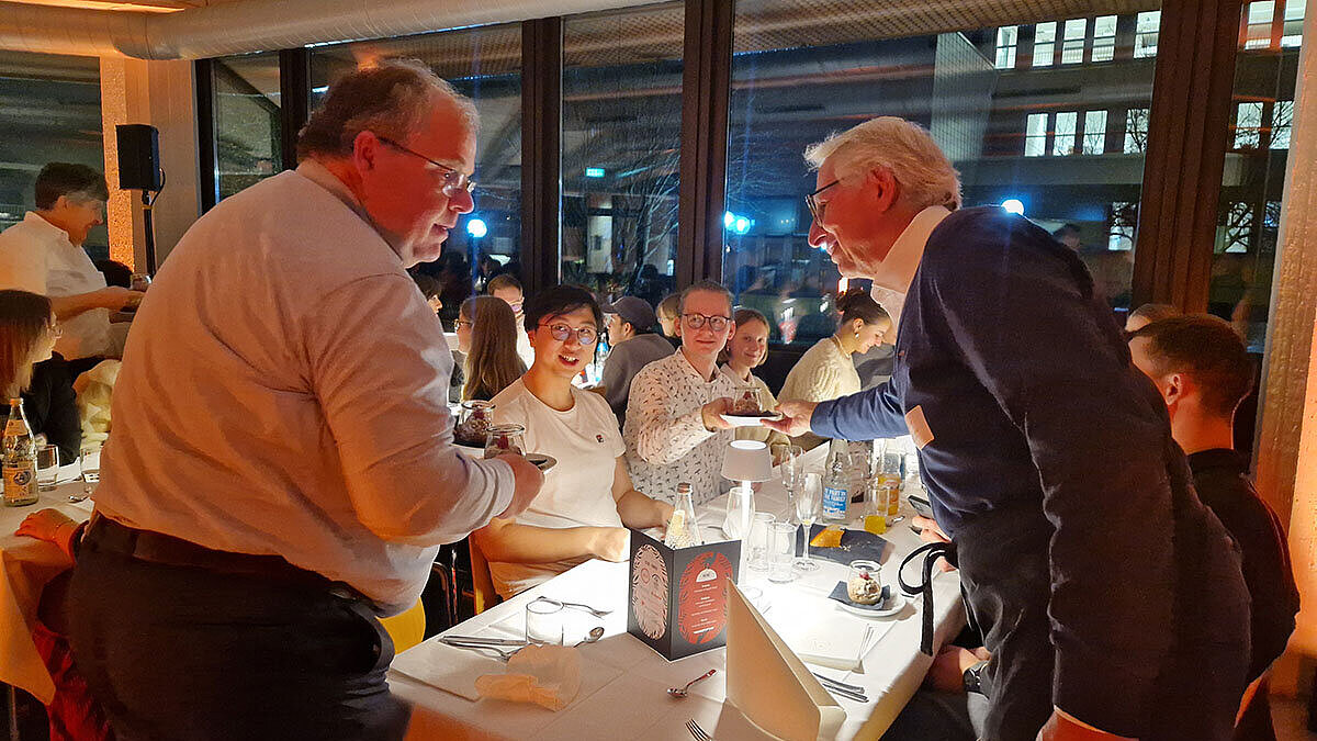 Prof. Dr. Andreas Brensing und Thomas Michel bringen die Nachspeise an die Tische