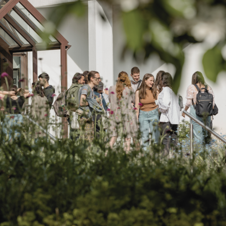 Studierende stehen in einer Gruppe vor dem E-Gebäude des Campus