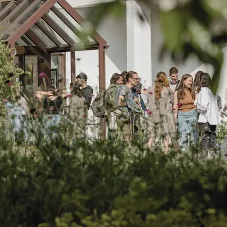 Studierende stehen in einer Gruppe vor dem E-Gebäude des Campus