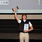 HSRM-Student Moritz Pähler steht während der Preisverleihung des exground filmfest 2024 auf der Bühne und reckt seinen Preis in die Höhe.