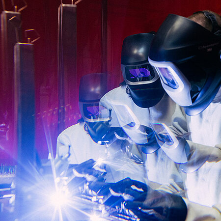 Mensch in Schutzausrüstung und Visier arbeitet mit einem Laser im Labor am Campus Rüsselsheim