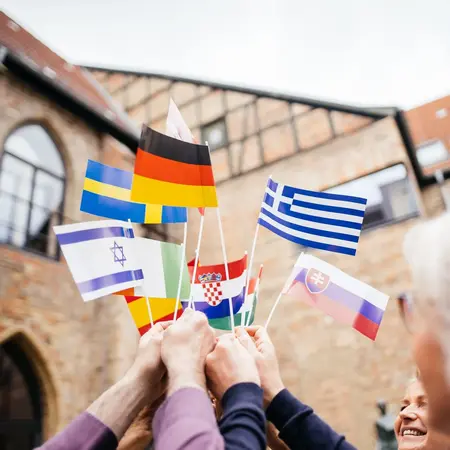 Grenzenloses Europa Es sind Hände zu sehen, die verschiedene EU und andere Papierflaggen in die Höhe halten