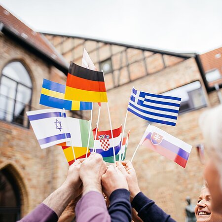 Grenzenloses Europa Es sind Hände zu sehen, die verschiedene EU und andere Papierflaggen in die Höhe halten