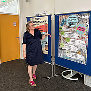 Prof. Dr. Marion Kamphans zeigt auf Plakate, die an Stellwänden angebracht sind.