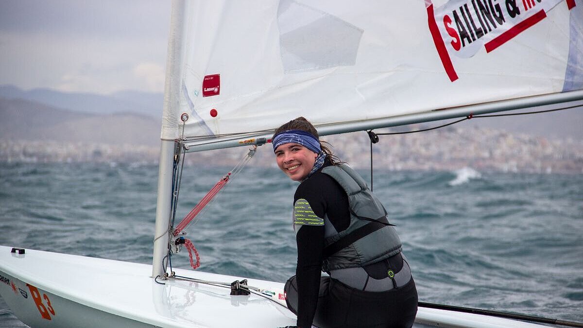 Porträt von Jennifer Weißenberger, Segeln Jennifer Weißenberger sitzt auf einem Segelboot und lächelt in die Kamera