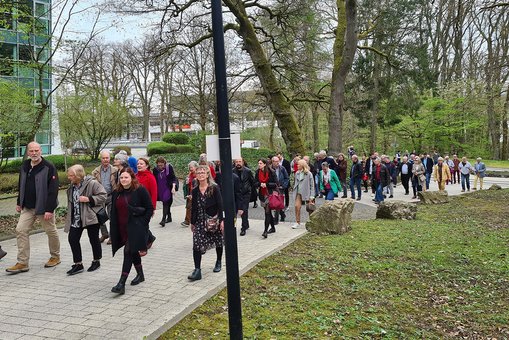 Personen laufen in einer großen Gruppe über den Campus Unter den Eichen der Hochschule RheinMain