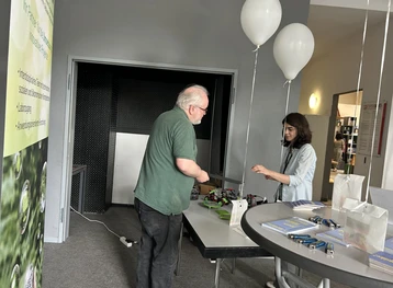 Ausstellung: Georg Derscheid erklärt einer Besucherin die Elektrolyse am Stand der Hochschule RheinMain. 