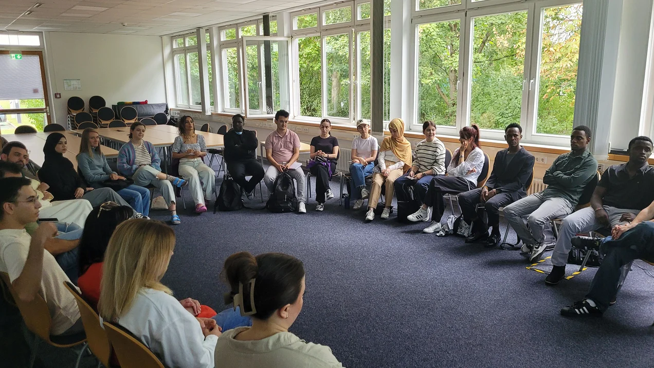 Eine Gruppe junge Menschen sitzt im Stuhlkreis zusammen.