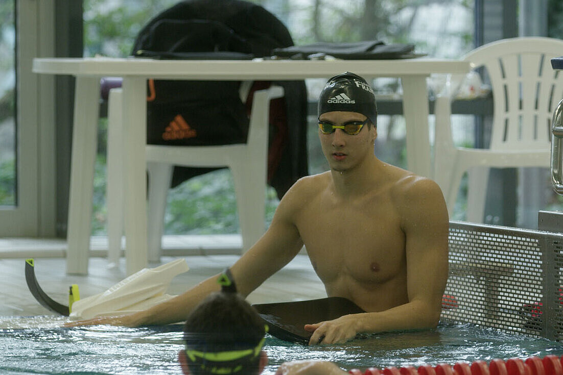 Lucas Matzerath sitzt am Beckenrand  eines Schwimmbeckens