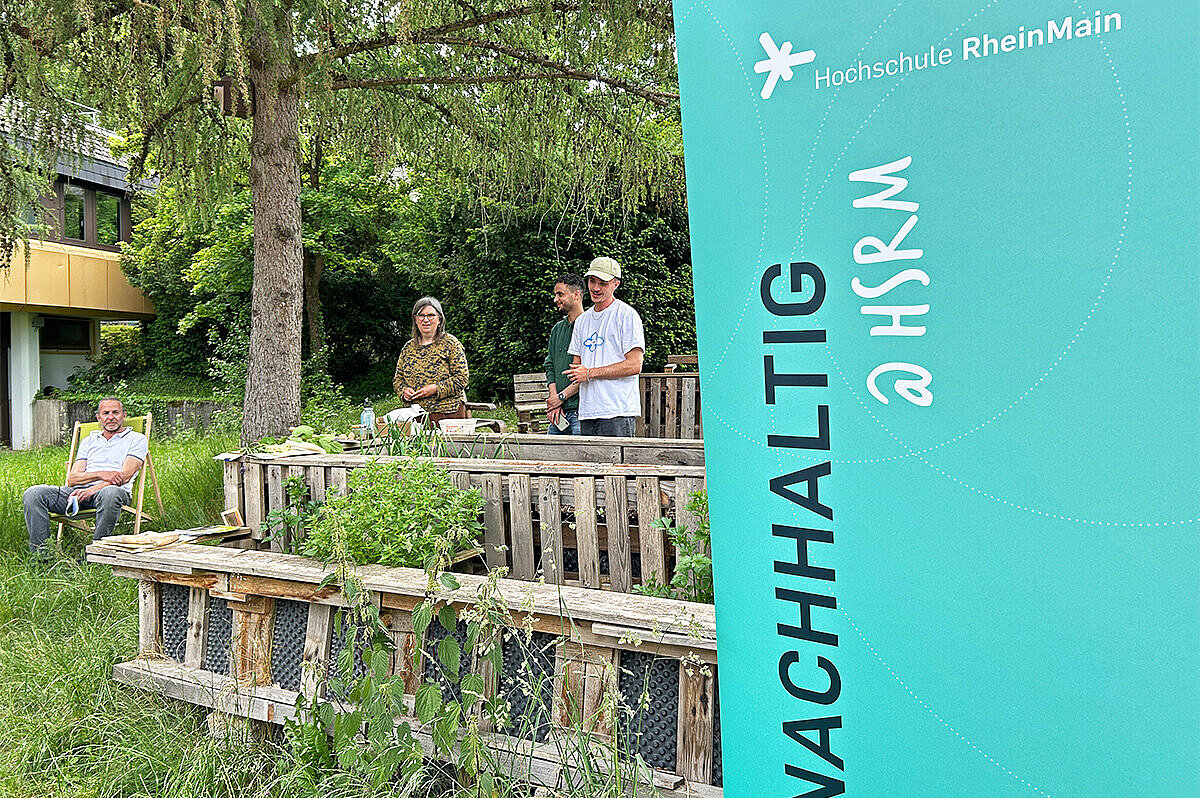 Mitarbeiter des Nachhaltigkeitsbrüs der Hochschule RheinMain stehen gemeinsam mit der Referentin Sybille Fuchs in Kurts Garten auf dem Campus Kurt-Schumacher-Ring der Hochschule RheinMain