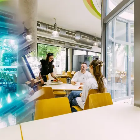 Studierende sitzen am Tisch in der Mensa