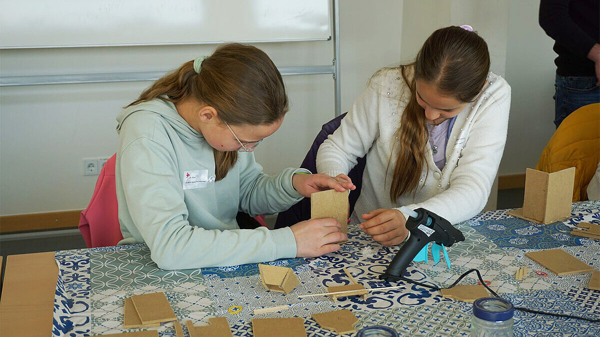 Teilnehmerinnen am Girls’Day 2025 sitzen an einem Tisch und arbeiten.