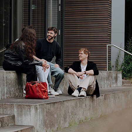 Studierenden sitzen auf den Treppen auf dem Campus der HSRM
