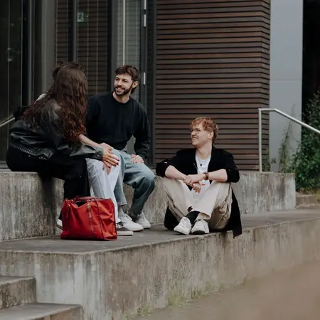 Studierenden sitzen auf den Treppen auf dem Campus der HSRM