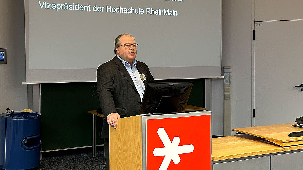 Prof. Dr. Andreas Brensing steht am Rednerpult des Audimax der Hochschule RheinMain