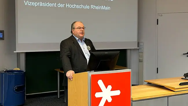 Prof. Dr. Andreas Brensing steht am Rednerpult des Audimax der Hochschule RheinMain