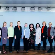 Eine Gruppe von zehn Personen aus bundeszentralen Organisationen der Senioren- und Pflegepolitik und die Bundesseniorenministerin Karien Prien steht lächelnd vor einer blauen Wand mit dem Logo des Bundesministeriums für Familie, Senioren, Frauen und Jugend. 