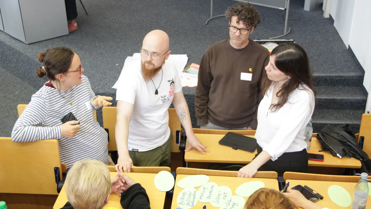 Eine Gruppe von fünf Personen diskutiert angeregt im Audimax der Hochschule RheinMain (HSRM). 