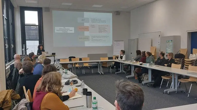 Vortag. Menschen sitzen in Tischen in einem Kreis 