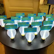 Auf einem Tisch stehen kleine, mit dem 3-D-Drucker erstellte Glühbirnen, auf denen der Schriftzug "RheinMain StartUpLabs | Innovation Camp 2025 zu lesen ist.
