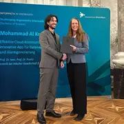 Prof. Dr. Eva-Maria Iwer und ein Absolvent der Hochschule RheinMain schauen in die Kamera.