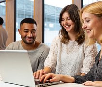 Drei junge Menschen arbeiten an einem Laptop.