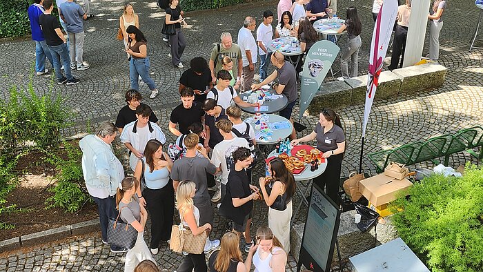 Schüler:innen im Innenhof der Wiesbaden Business School im Gespräch mit aktuellen Studierenden.